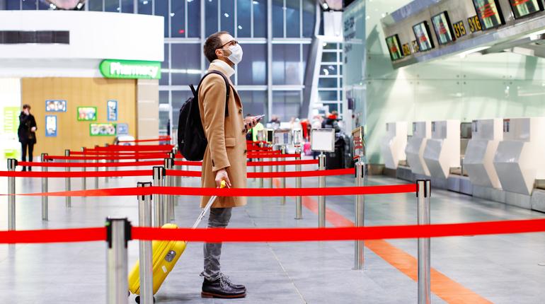 Man in mask at empty airport with luggage in coronavirus quarantine isolation, waiting for departure, flight cancellation, pandemic infection worldwide spread, travel restrictions and border shutdown